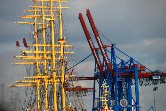 Gigantisch groß und filigran zugleich: stählerne Rädchen im Getriebe der Globalisierung - Ein alter Segler und moderne Hafentechnik: die nahezu emissionsfreie PEKING und Containerbrücken für viermal so lange, ähnlich hohe Frachter, jedoch mit 170-fache Nutzlast an der Elbseite des Hamburger Burchardkais am 7.9.2020 &copy; Andreas Zedler